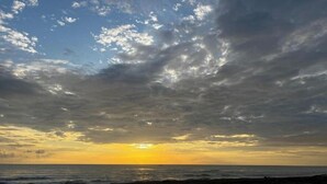 Una playa con un atardecer, nubes y el océano.