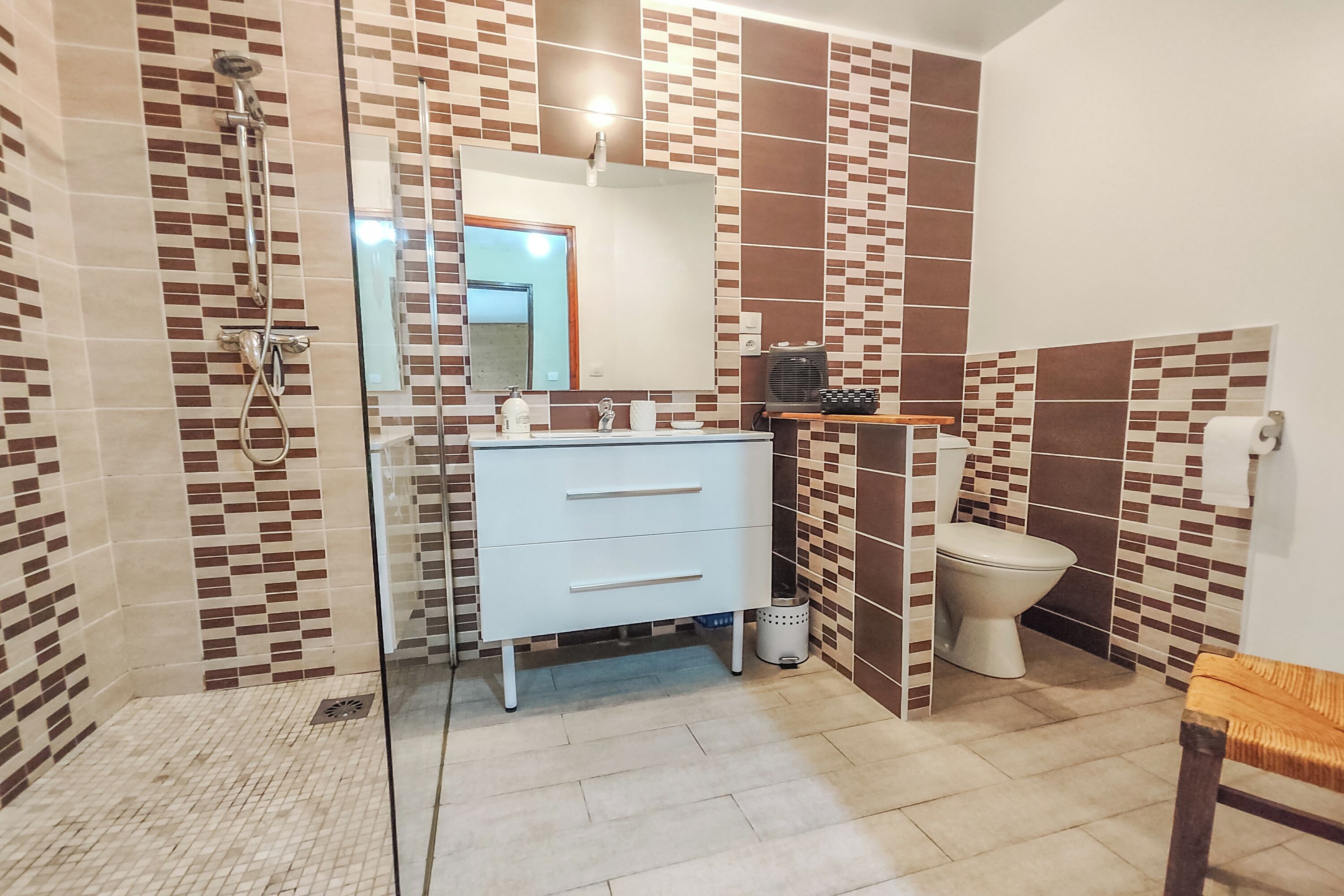 A bathroom with a shower, toilet, and a sink with a mirror.