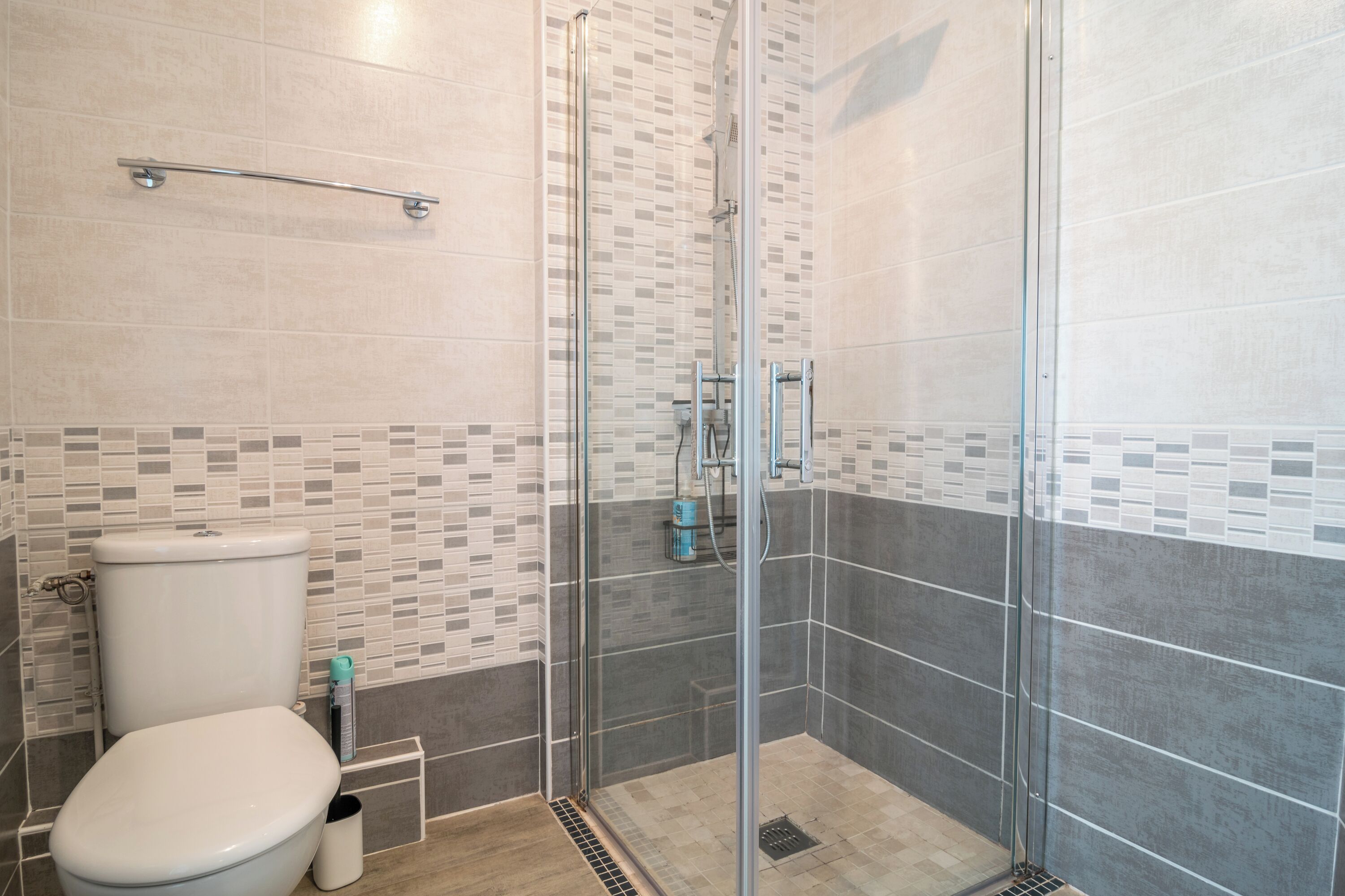 A bathroom with a glass-enclosed shower, a toilet, and tiled walls.