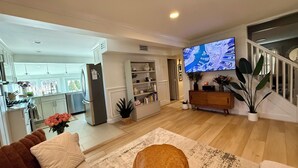 Een moderne woonkamer met een flatscreen televisie, een bank, een salontafel en een keuken op de achtergrond.