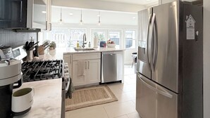 Een moderne keuken met roestvrijstalen apparatuur, witte kastjes en een groot raam voor natuurlijk licht.