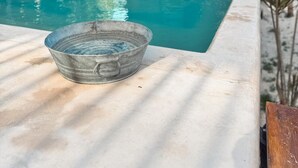A swimming pool with a metal bowl on the edge, surrounded by palm trees and a building with a balcony. - Chic Loft Steps from the Jungle View (Holbox)