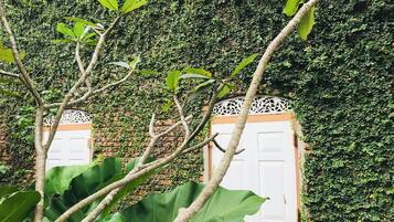 Edifício parcialmente coberto por hera, com duas portas brancas e detalhes decorativos.