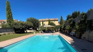 Piscina rectangular con borde de azulejos, rodeada por una terraza pavimentada.