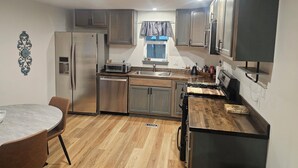 A compact kitchen with a refrigerator, stove, sink, and wooden flooring. - Cuatros Pinos ~ Quiet Tall Pine Retreat (Durango)