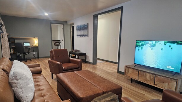 A modern living room with a leather sofa, ottoman, and a television displaying 'Love Nature'. - Cuatros Pinos ~ Quiet Tall Pine Retreat (Durango)