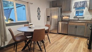A modern kitchen with a dining area, stainless steel appliances, and a herringbone wood floor. - Cuatros Pinos ~ Quiet Tall Pine Retreat (Durango)