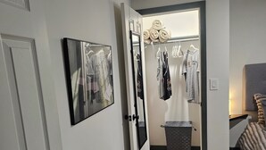 A hallway with a white door, a framed picture, a gray fur rug, and a clothing rack with various garments. - Cuatros Pinos ~ Quiet Tall Pine Retreat (Durango)