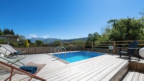 A wooden deck with a pool, lounge chairs, and a view of mountains. - Apartment with private pool in Annecy (Annecy)