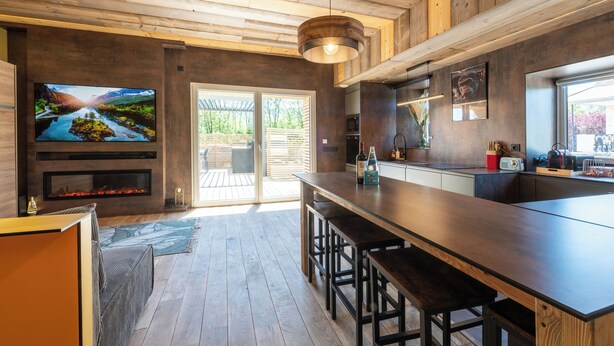 A modern kitchen with a wooden ceiling, a large TV, and a bar area. - Apartment with private pool in Annecy (Annecy)