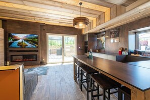 Eine moderne Küche mit Holzboden, einem großen Fernseher und einer Bar.