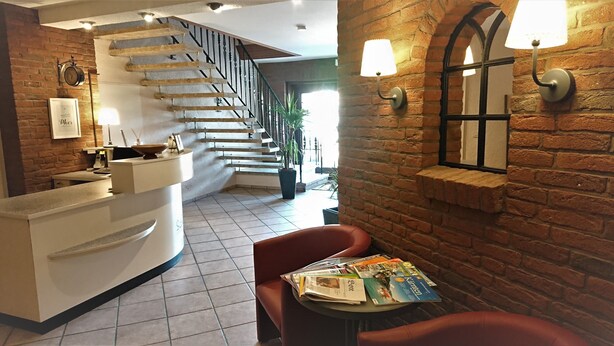 A reception area with a staircase, a reception desk, and a seating area with magazines. - Boardinghouse Kappeln by Team SchleiFee (Kappeln)