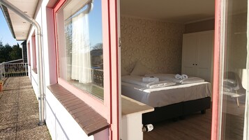 A bedroom with a bed, a window, and a door.