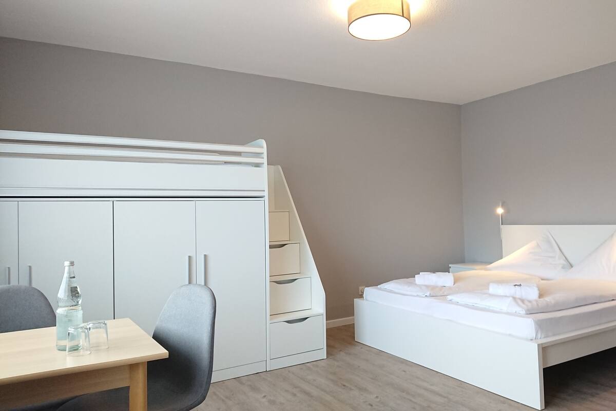 Een moderne slaapkamer met een bed, bureau en kledingkast.