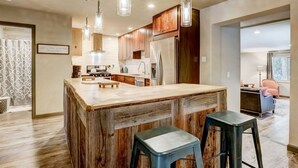 A modern kitchen with wooden accents, a central island, bar stools, and pendant lighting. - Miztec Magic - Ping Pong+Air Hockey+Basketball Gm (South Lake Tahoe)