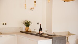 A modern kitchen with a central island, a potted plant, wine glasses, and a wine bottle.