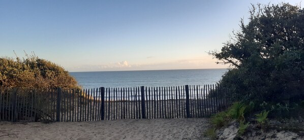 Una spiaggia con una recinzione di legno in primo piano e una vista limpida sul mare.
