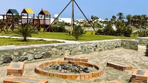 A sandy area with a circular stone structure and wooden benches. - House in front of the sea, with swimming pool, terrace, barbecue, Pet friendly! (Asia)