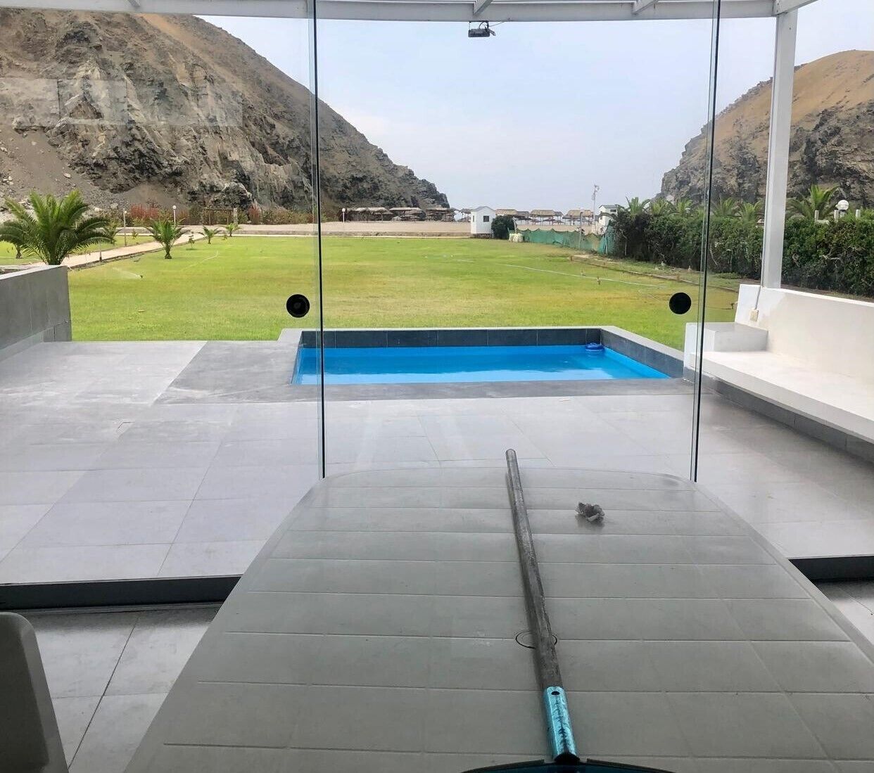 A pool area with a view of a mountainous landscape, a clear sky, and a modern outdoor seating area.