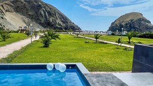 A swimming pool with a view of a mountainous landscape and a playground in the background. - House in front of the sea, with swimming pool, terrace, barbecue, Pet friendly! (Asia)