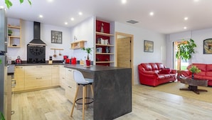 A modern kitchen with a central island, wooden cabinets, and a red sofa in the living area.
