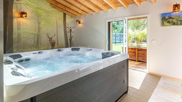 A hot tub in a room with a wooden ceiling and a large window.