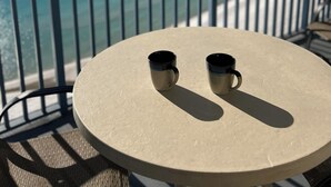 A round table with two black mugs on a balcony overlooking the ocean. - Cozy beachside condo, great location, and fantastic views/sunsets (Panama City Beach)