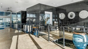 A modern hotel lobby with a glass partition, a water feature, and a large blue vase. - Cozy beachside condo, great location, and fantastic views/sunsets (Panama City Beach)