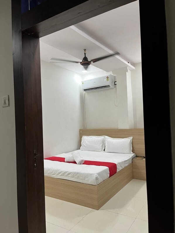 Una habitación de hotel con una cama, un ventilador de techo y un equipo de aire acondicionado.