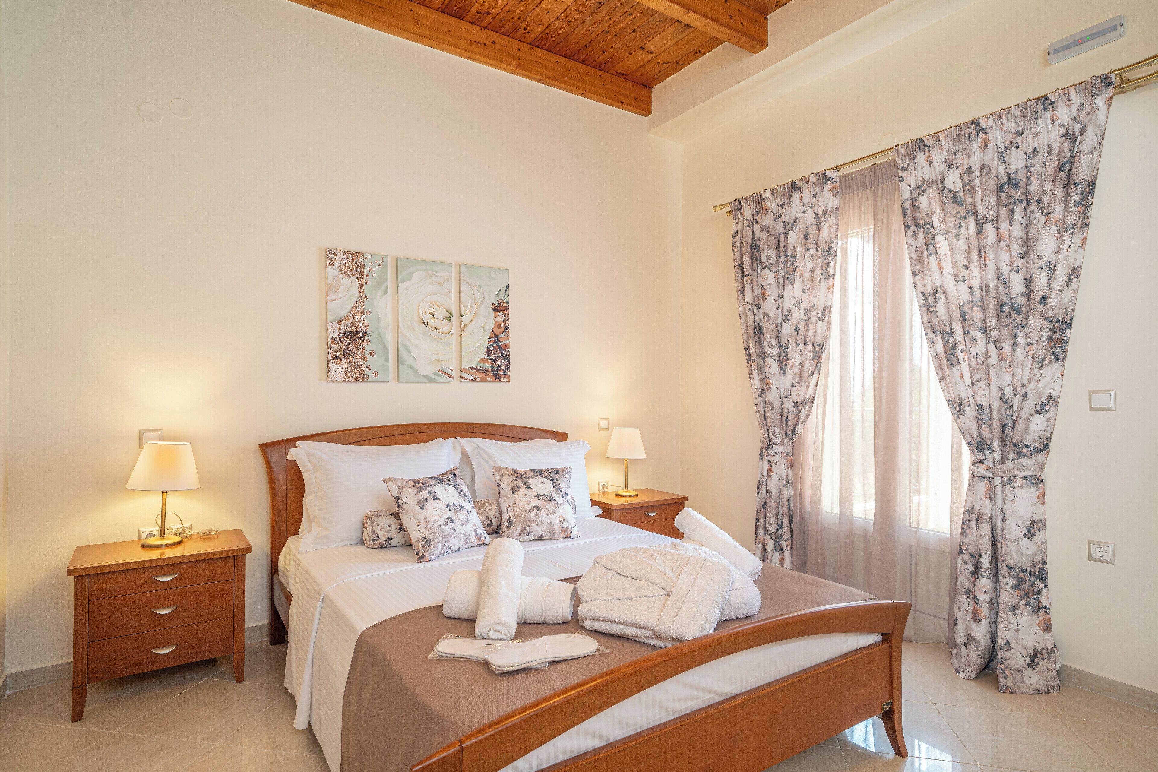 A neatly made bed with white bedding, two bedside tables with lamps, and floral curtains.
