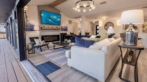 Un salon moderne avec une cheminée, un grand téléviseur et un lustre.