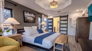 Une chambre à coucher moderne avec un grand lit, des lampes de chevet, un banc en bois et un placard à portes coulissantes.