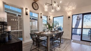Un espace repas moderne avec une grande table, quatre chaises et une vue sur l’extérieur.