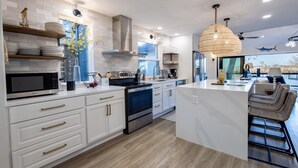 A modern kitchen with white cabinetry, stainless steel appliances, and a central island. - Lakefront Getaway in Texas Hill Country | Dock, Kayaks, Pickleball, Jet Ski (New Braunfels)