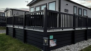 Ett husvagn med svart exteriör, vita detaljer och en liten veranda. Det finns en skylt som visar att det är enhet nummer 21.