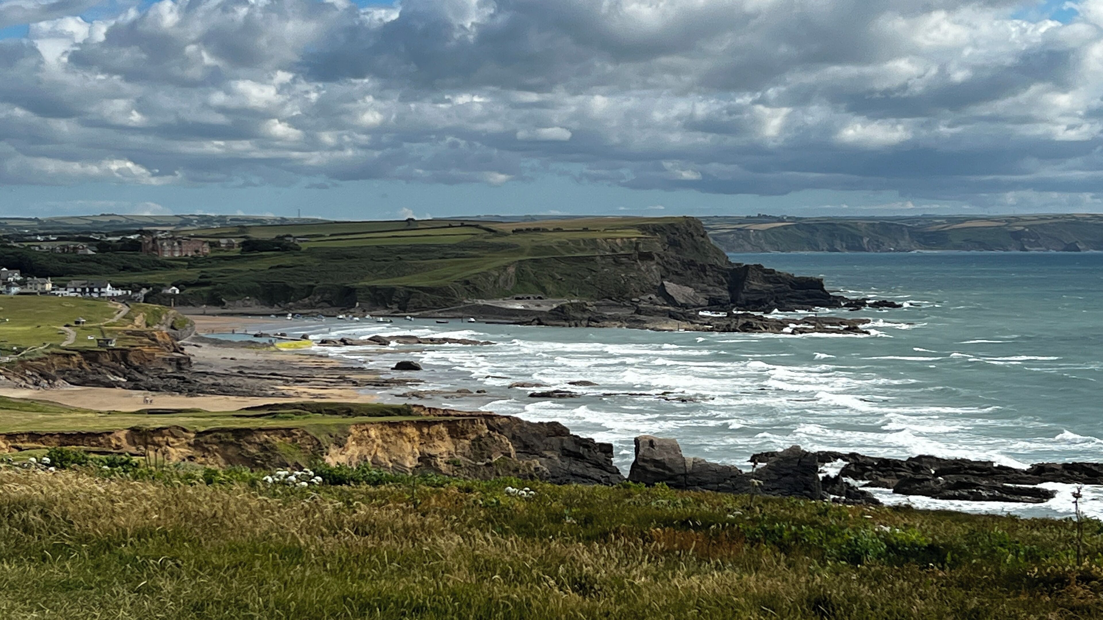 Un paysage côtier avec des falaises, une plage et un village.