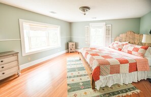 Une chambre à coucher avec un lit en bois, une commode et deux fenêtres équipées de volets.