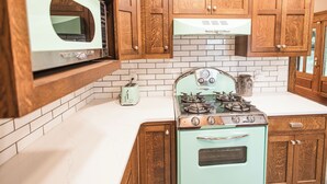 A kitchen with wooden cabinets, a vintage stove, and a microwave.