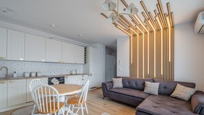 Une cuisine moderne avec des meubles blancs, une table à manger en bois et un tapis à motifs gris.