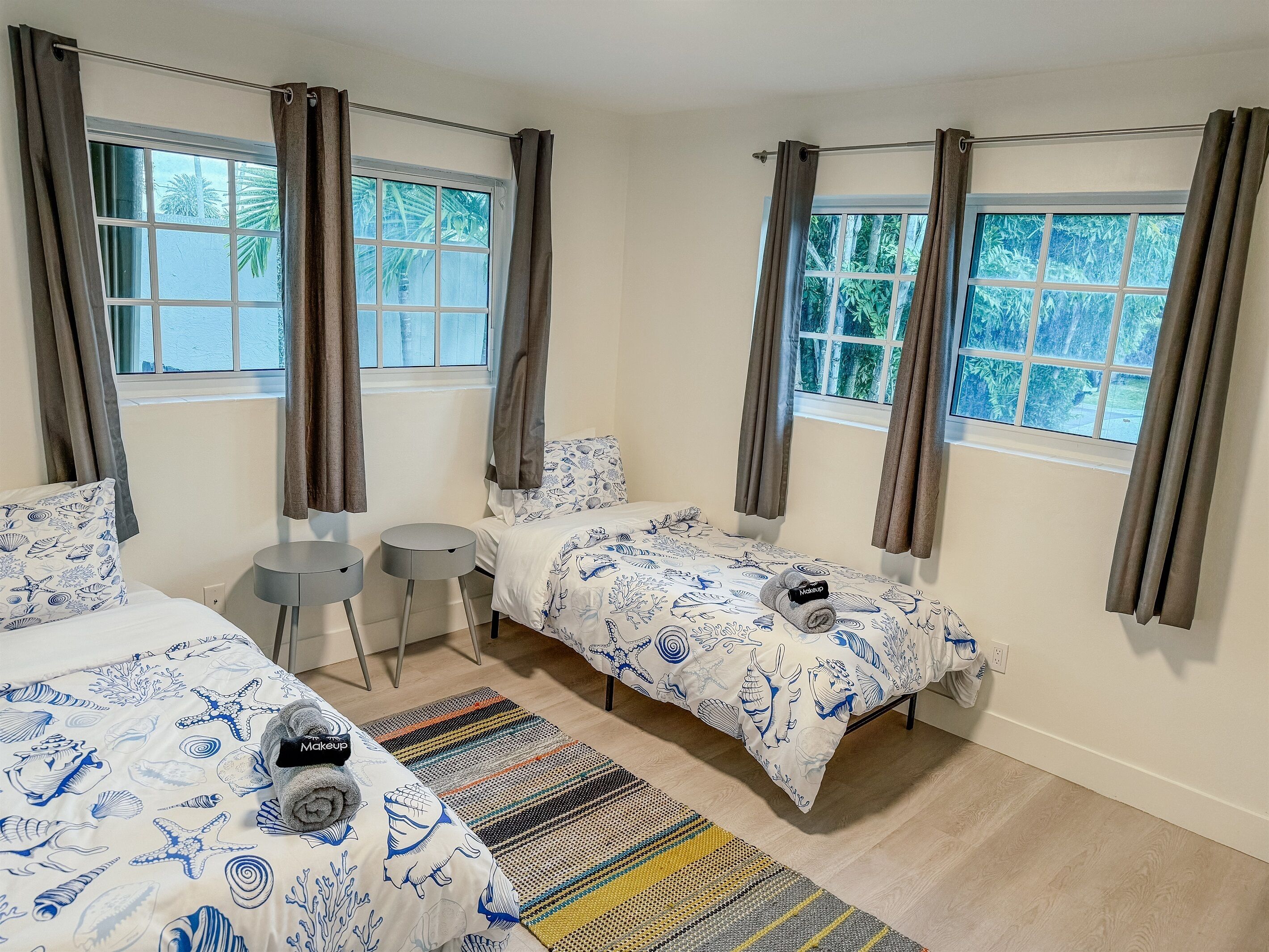 A hotel room with two beds, a small table, and a window with curtains.