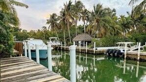 A marina with boats docked, a wooden dock, and a thatched-roof structure.