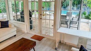 A room with a large sliding glass door leading to an outdoor patio area with a pool and seating.