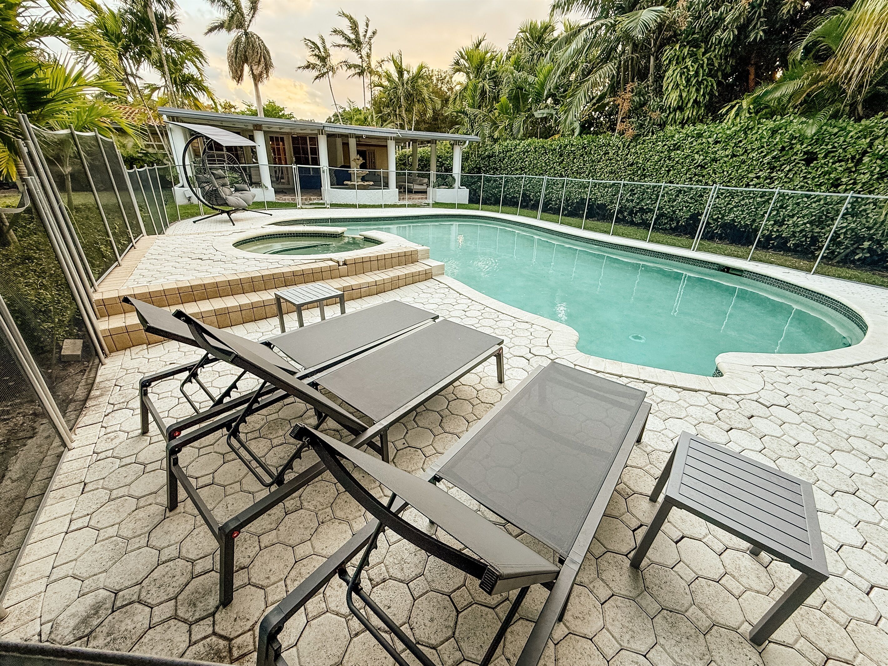 Un área de piscina con baldosas hexagonales, tumbonas y un jacuzzi.