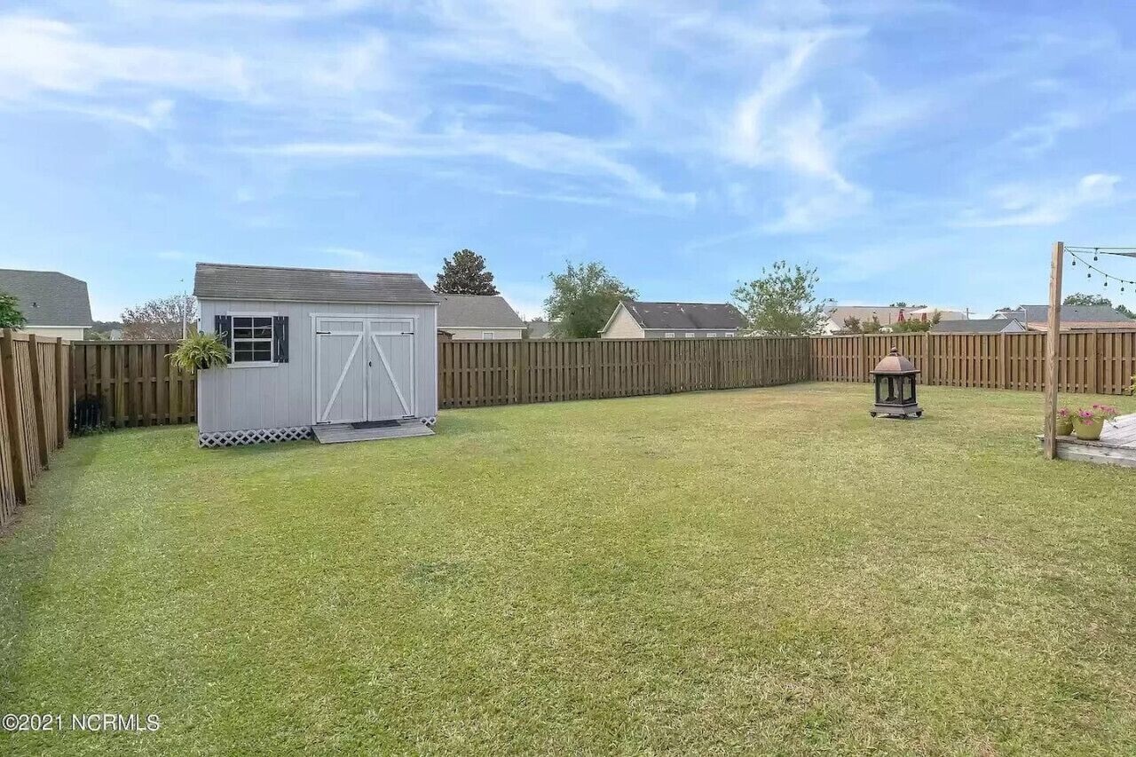 Ein Garten mit Schuppen, Holzpforte und Laterne.