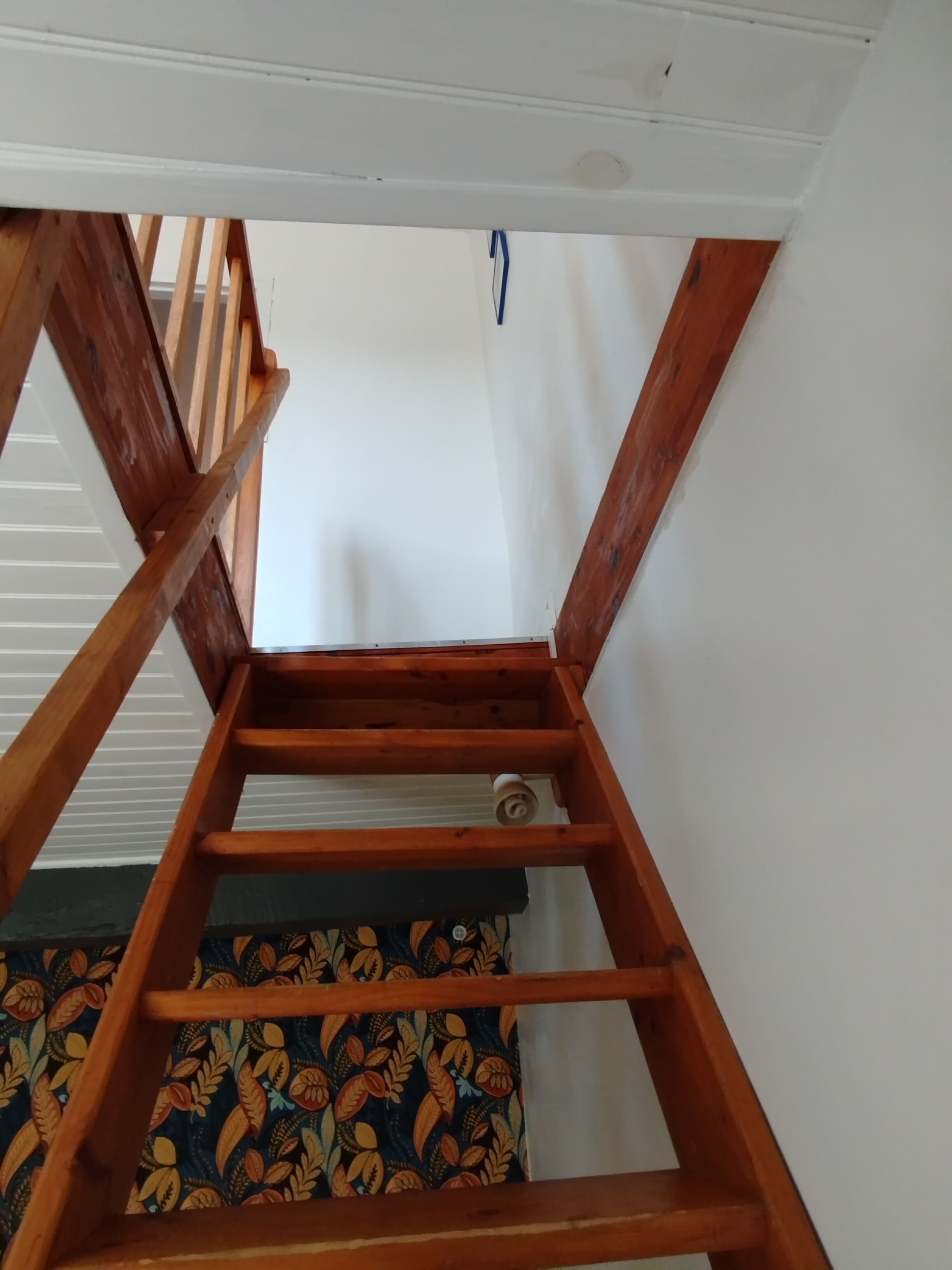 Een houten trap met een patroonkussen onderaan.