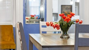 Un comedor con una mesa de madera, sillas y un florero con tulipanes rojos.