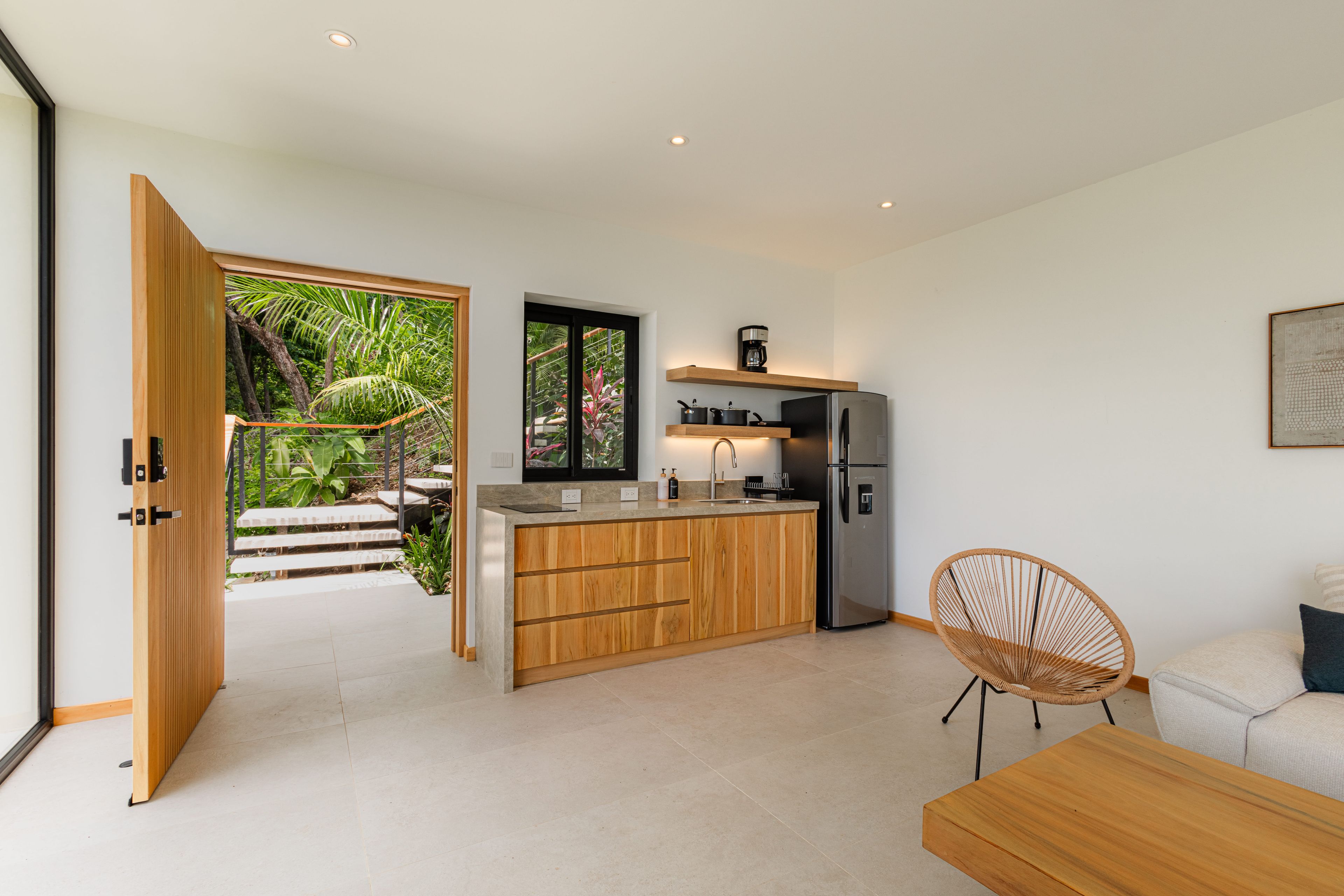 Une cuisine moderne dotée d’un îlot central en bois, d’appareils électroménagers en acier inoxydable et offrant une vue sur un jardin luxuriant.