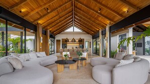 Amplia sala de estar con techo de madera alto, sofás grises grandes y una mesa de centro.