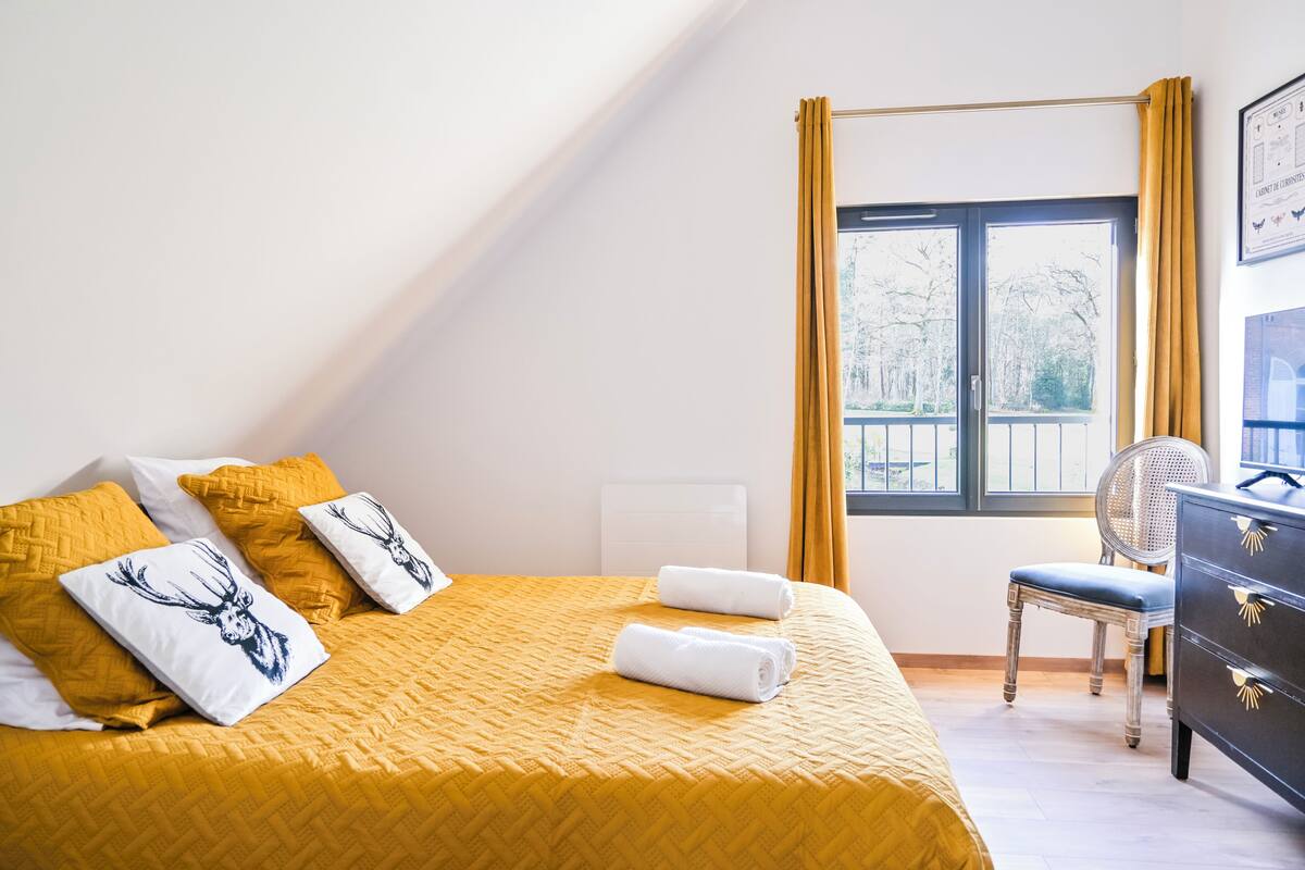 Une chambre d’hôtel avec un lit, une chaise, une commode et une fenêtre avec des rideaux.