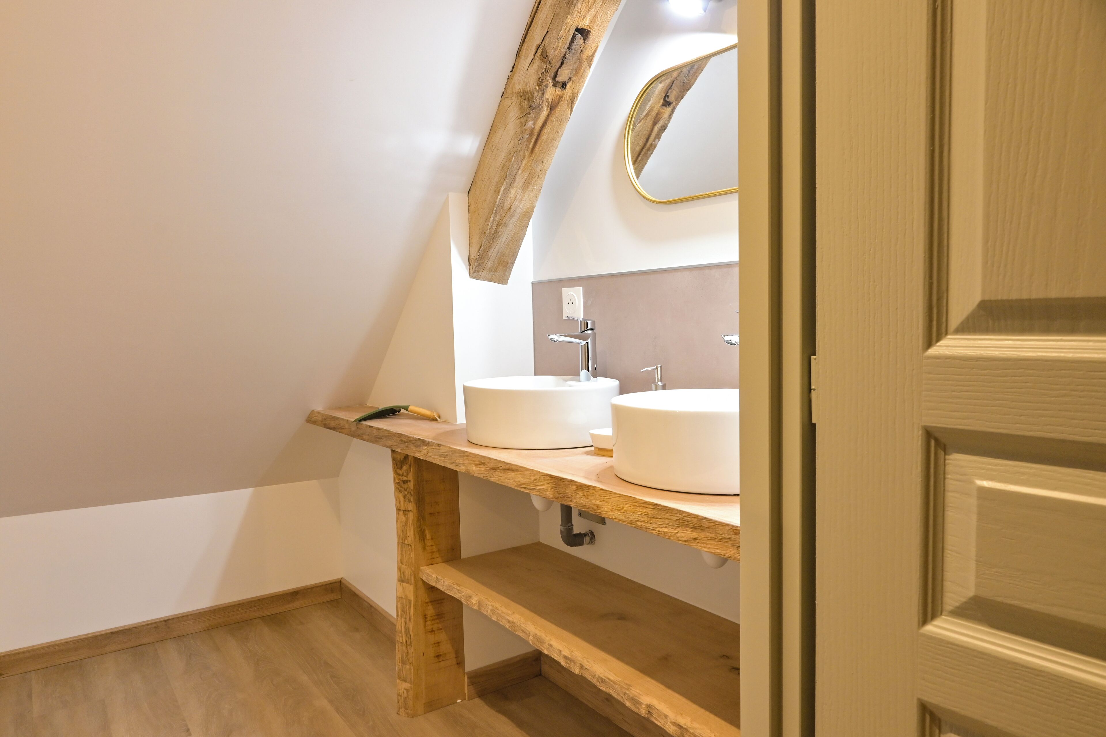 A bathroom with a wooden vanity, two white sinks, and a mirror.